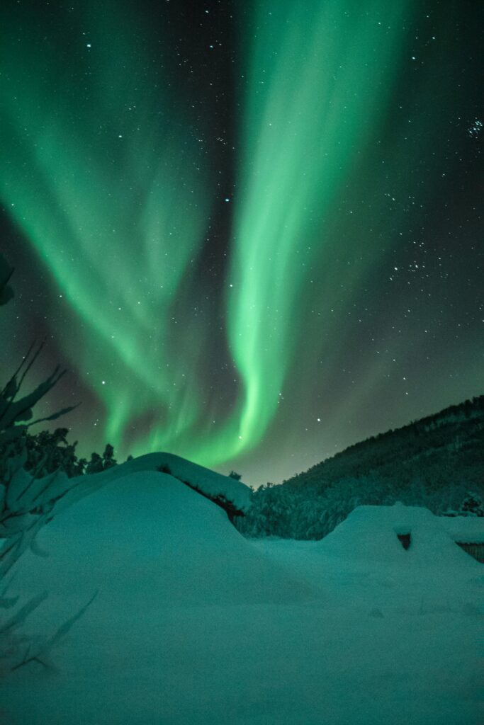 Breathtaking view of aurora borealis dancing over snow-covered terrain.