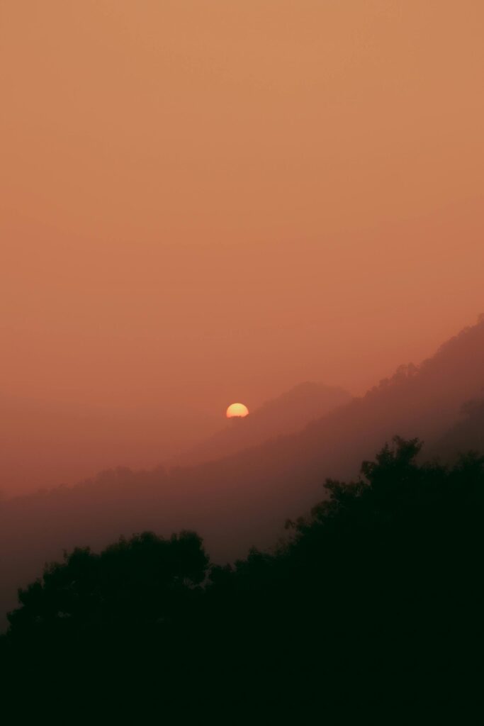 Sunrise over misty mountains with warm hues and dramatic sky.