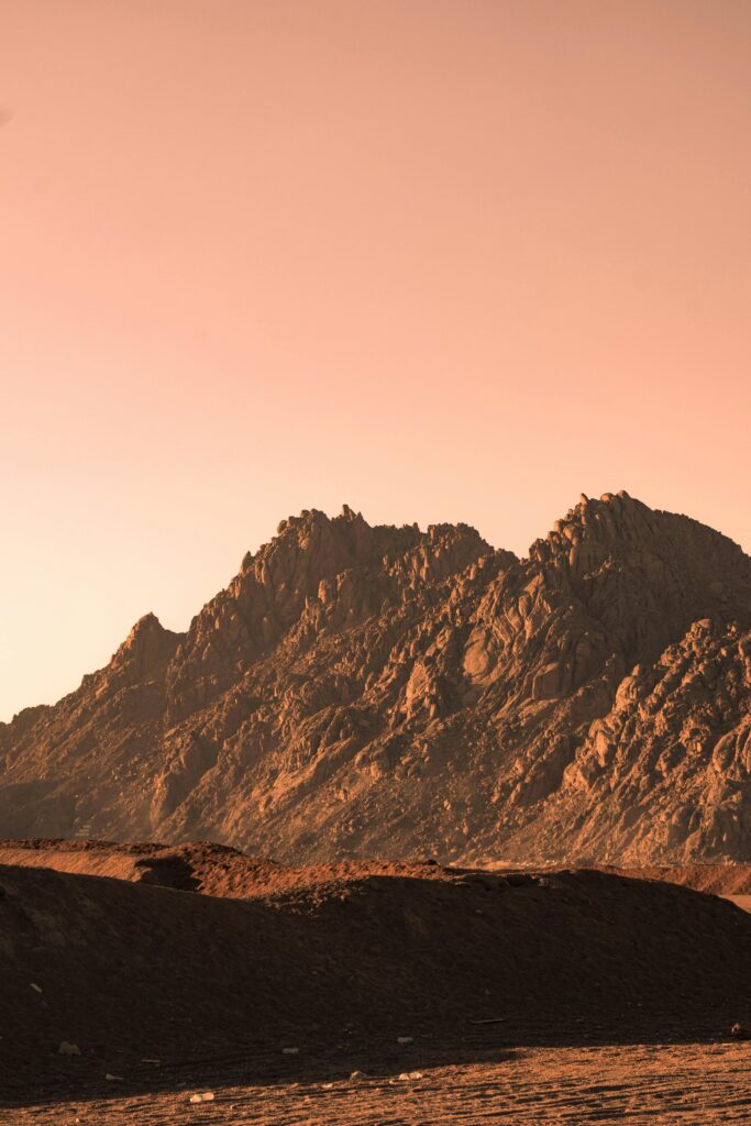Beautiful mountains in the Sinai desert under a warm orange sunset glow.